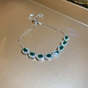 Detalle macro de una pulsera de lujo ajustable con siete circonitas verdes de forma oval.