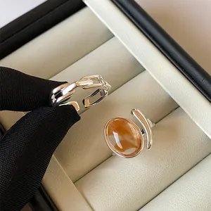 Close-up of elegant silver open rings with oval amber marbled stone in a jewelry box