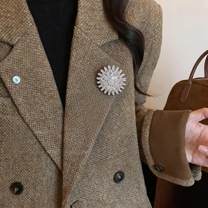 Gros plan d'une broche fleur scintillante avec zircons sur un manteau en tweed marron