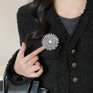 Vue détaillée d'une broche fleur en zircone plaquée or 18 carats avec perle.