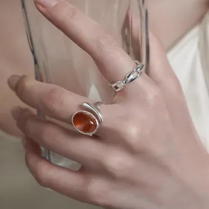 Close-up of minimalist silver rings with oval brown gemstone and chain link design