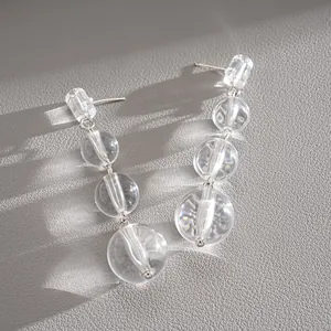 Vue détaillée de boucles d'oreilles minimalistes à perles de cristal sur cuir gris