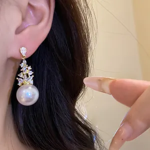 Elegant close-up view of vintage pearl drop earrings with zircon floral accents on a model