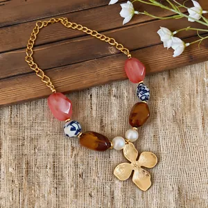 Detalle del collar de estilo vacacional con cuentas de cerámica y colgante de flor dorada