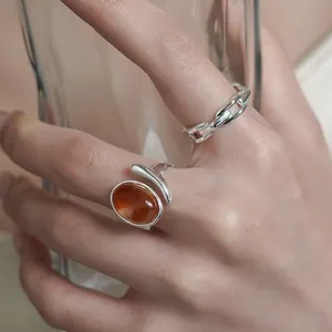 Close-up of elegant amber resin oval ring and minimalist silver link chain ring on finger
