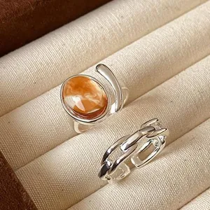 Detail of silver rings set with marbled orange cabochon and chain link band