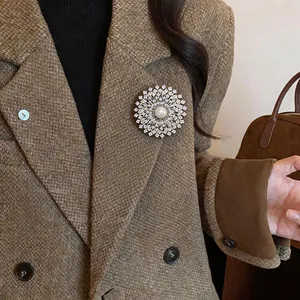 Élégante broche fleur plaquée or 18k avec perle sur une veste en tweed.