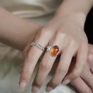 Close-up of elegant silver open ring with oval amber stone and chain-link band on hand