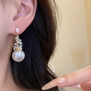 Elegant vintage style pearl pendant earrings with marquise zircon stones worn on ear