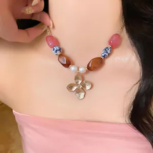 Detalle de un collar de perlas floral de estilo playero con cuentas de cerámica azul.