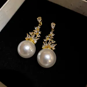 Detail of elegant retro gold earrings with marquise zircons and large white pearls