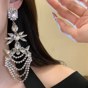 Dettaglio squisito di orecchini geometrici con strass e nappe a goccia d'acqua su modella.