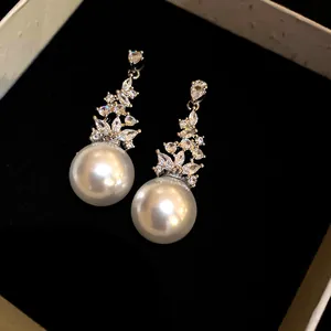 Close-up of elegant pearl drop earrings with a sparkling zirconia floral design in a box