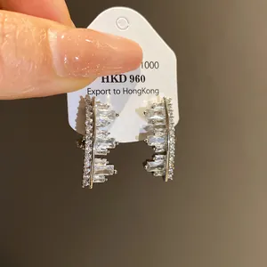Macro detail of irregular geometric ear clips featuring shimmering clear zircon stones set in silver.