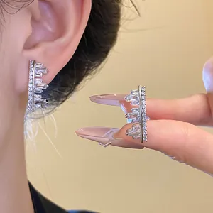 Close-up of elegant geometric cubic zirconia ear clips with vintage silver finish.