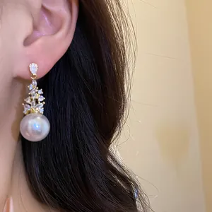 Close-up detail of vintage pearl drop earrings with sparkling zircon accents on model