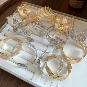 Detailed view of vintage gold and silver leaf and flower open cuff bracelets on a tray