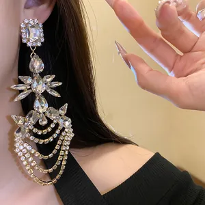 Primo piano di eleganti orecchini geometrici con strass e nappe su una modella