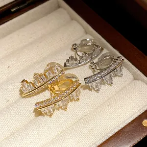 Close-up detail of irregular geometric zircon ear clips in gold and silver colors