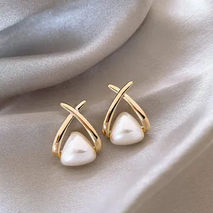 Close-up of French style cream white pearl earrings with gold-toned cross design
