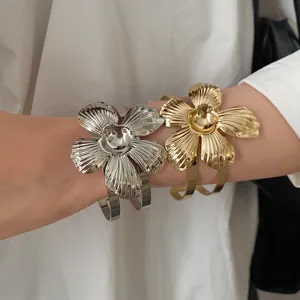 Macro detail of retro gold and silver metallic flower cuff bracelets with leaf texture