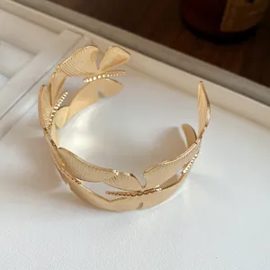 Detailed close-up of vintage gold cuff bracelet featuring intricate leaf wing textures