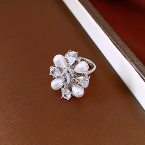 Macro detail of an elegant flower-shaped ring with pearls and brilliant cubic zirconia