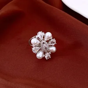 Close-up detail of elegant 14k gold plated flower ring with white pearls and shiny CZ