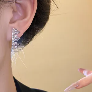 Close-up detail of sparkling irregular geometric zircon earrings worn on a model's ear.