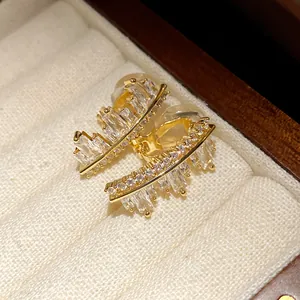 Macro detail of irregular geometric gold-tone ear clips with sparkling zircons
