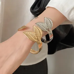 Detailed close-up of gold and silver metal cuff bracelets with leaf texture design