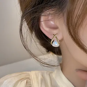 Close-up of elegant French style creamy white heart pearl earring with gold cross frame