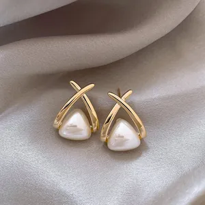 Detail view of elegant French-style gold-plated earrings with cream triangular pearls