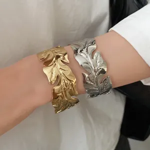 Detail view of stylish metal leaf-patterned open bangles in gold and silver finishes