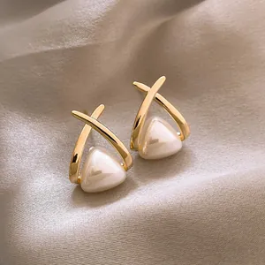 Close-up of elegant triangular pearl earrings on champagne silk background