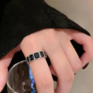 Anello vintage color argento con pietre nere esagonali indossato sul dito di una modella
