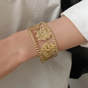 Elegant gold-tone open cuff bracelet featuring intricate floral texture on wrist