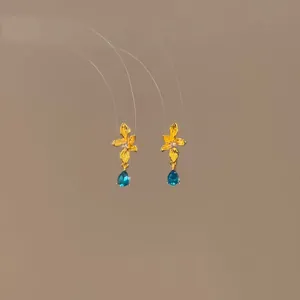Detail of gold flower earrings featuring elegant blue teardrop zircon stones.