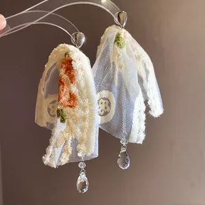 Detail view of embroidered lace floral earrings with sparkling crystal waterdrop drops