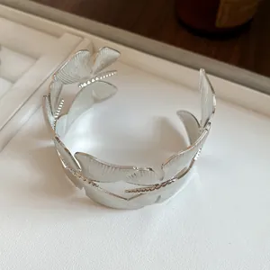 Detailed close-up of a silver metal leaf texture cuff bracelet with vintage design