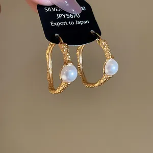 Dettaglio di orecchini a cerchio vintage in oro martellato con eleganti perle