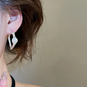 Dettaglio di orecchino vintage in argento a forma di C con perla e texture stropicciata