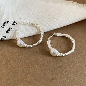 Dettaglio di orecchini a cerchio vintage in argento stropicciato con perle