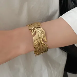 Detailed close-up of a vintage gold-toned metal leaf textured open cuff bracelet for women
