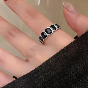 Dettaglio ravvicinato di un anello vintage aperto con pietre nere esagonali su un dito