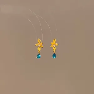 Close-up of elegant gold flower stud earrings featuring blue teardrop zircon drops