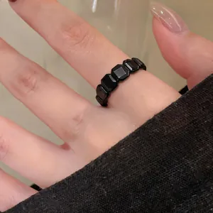 Dettaglio di un anello vintage nero con pietre esagonali indossato su un dito elegante.