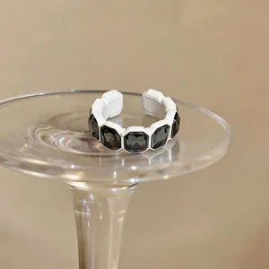 Dettaglio ravvicinato di un anello vintage esagonale con gemme scure e montatura bianca.