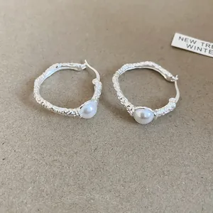 Primo piano di orecchini a cerchio vintage in argento con eleganti perle bianche