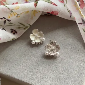 Close-up of asymmetric flower earrings with enamel, rhinestones and delicate pearls